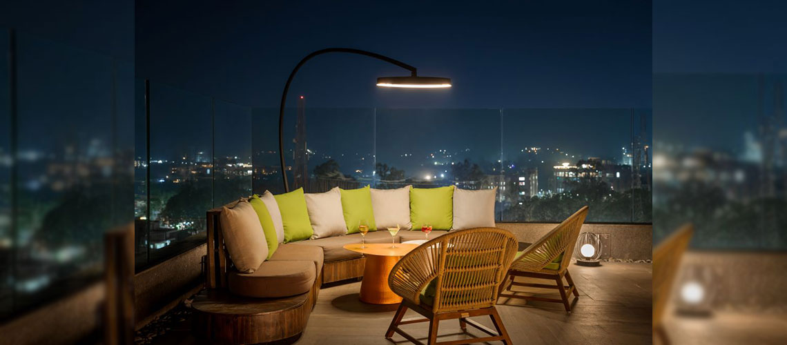 One Freestanding Heater with Light Hanging Over Seating Area of a Rooftop Patio