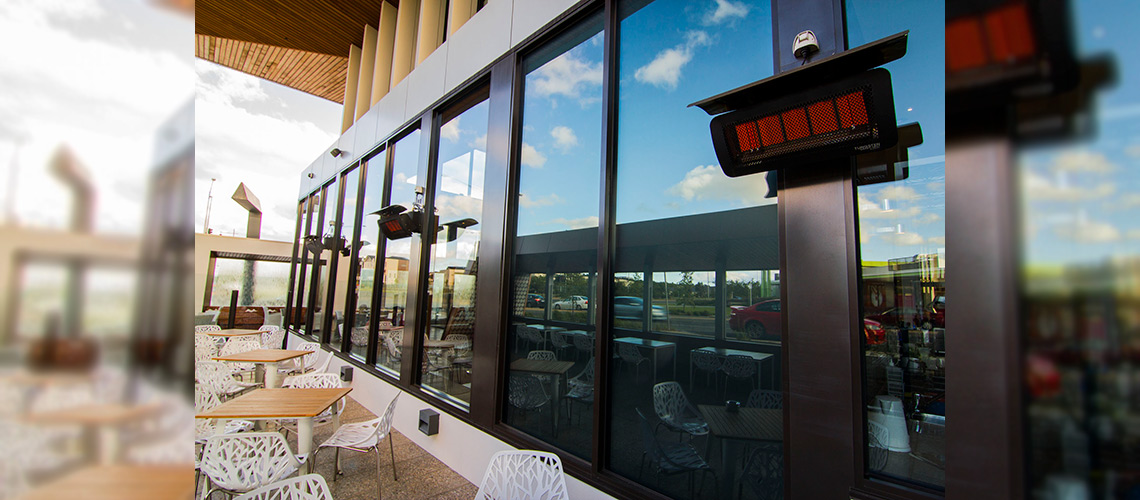 Three Gas Patio Heaters Wall Mounted Above Tables on the Rooftop Patio of a Restaurant 